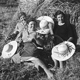 Tre donne con falci e cappelli, soddisfatte del loro lavoro, si riposano sulle manne, grossi fasci di spighe da loro stesse mietute.